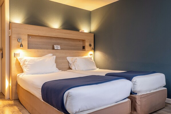 A double bed with a wooden headboard, two bedside tables with lamps, and a blue accent wall. - Kyriad Digne les Bains (Digne-les-Bains)