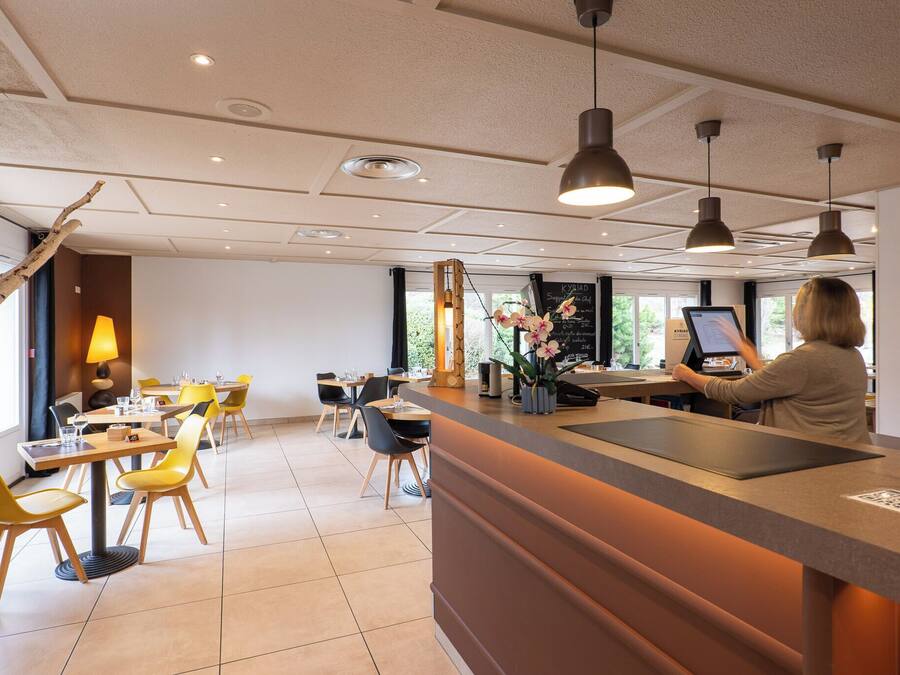 Un moderno vestíbulo de hotel con un mostrador de recepción, sillas amarillas y un amplio ventanal con vistas al exterior.