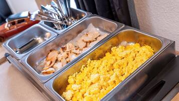 Een buffet met diverse gerechten, waaronder roerei en vleesschotels.
