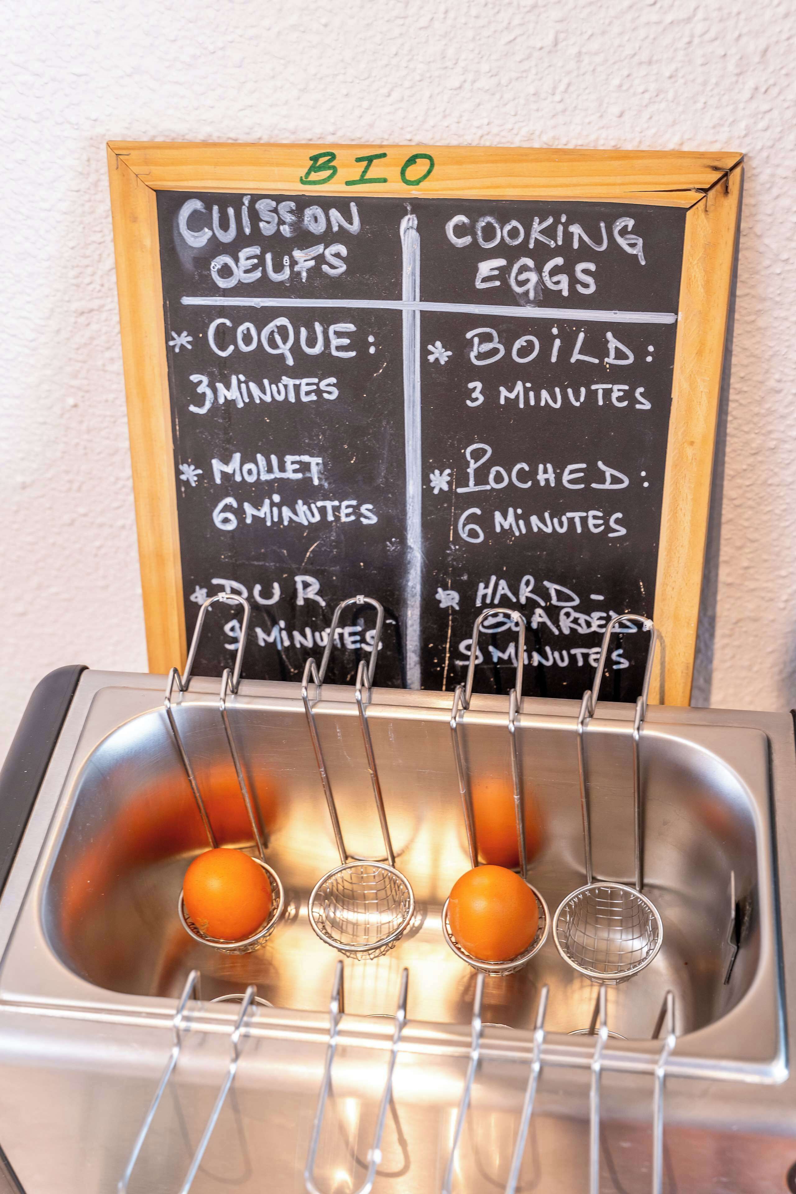A kitchen sink with eggs being boiled and a chalkboard with cooking instructions.