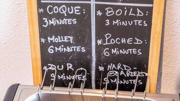 A kitchen sink with eggs being boiled and a chalkboard with cooking instructions.