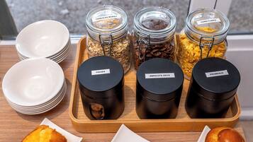 A breakfast buffet with labeled jars of cereals and black containers of spreads.