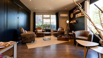 Una sala moderna con suelo de madera oscura, sofás de cuero, una mesa de centro y una estantería.