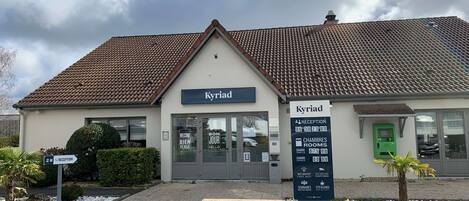 A hotel named 'Kyriad' with a reception area, rooms, and amenities like WiFi, security cameras, and breakfast.
