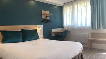 Una habitación de hotel con una cama grande, un escritorio y una ventana con cortinas.