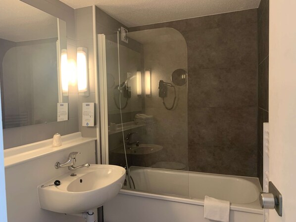 A bathroom with a white sink, a glass-enclosed shower, and a large mirror.