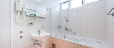Un baño moderno con lavamanos, espejo y bañera.