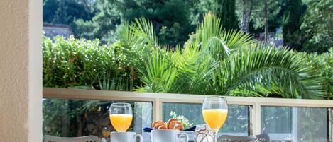 Un desayuno con dos vasos de jugo de naranja, un plato de pasteles y una bandeja en una mesa de balcón.