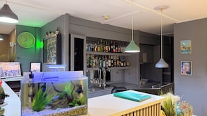 A bar area with shelves of liquor bottles, a clock, and a fish tank.