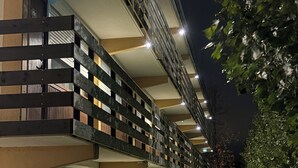 A modern hotel with a row of rooms, each with a balcony and a window.