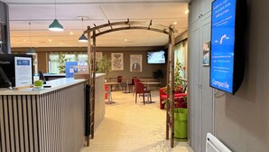 A reception area with a counter, chairs, a TV screen, and a wooden archway.