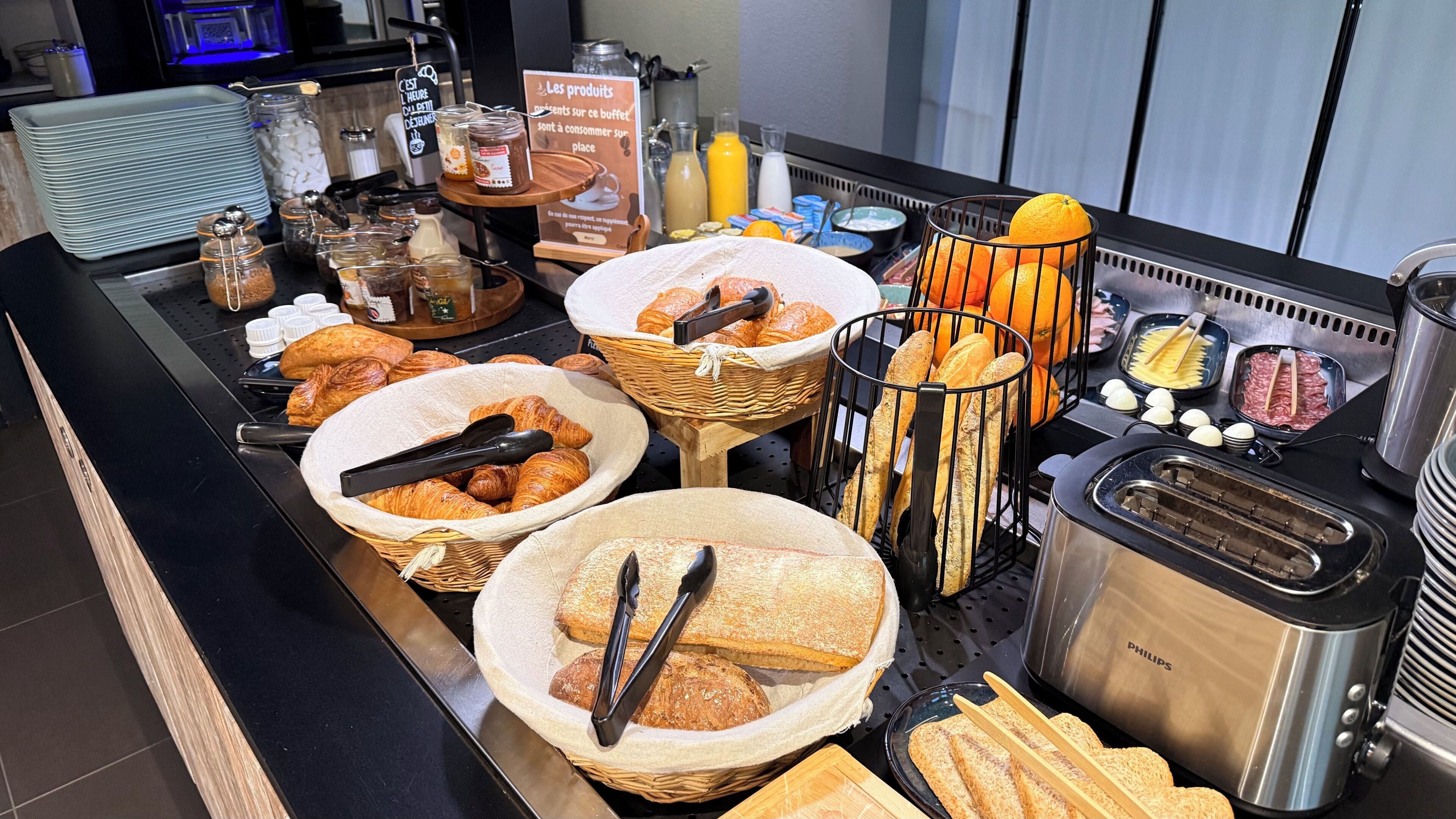 A buffet with various food items, including bread, pastries, and condiments.