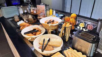A buffet with various food items, including bread, pastries, and condiments.