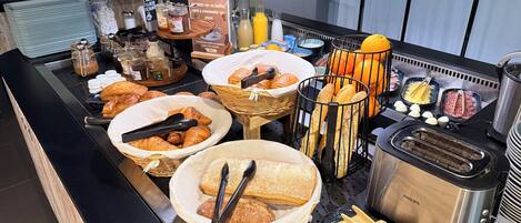 Un bufé con diversos alimentos, como pan, pasteles y salsas.
