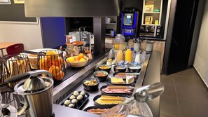 Una barra de buffet con diversos alimentos, entre ellos frutas, salsas y platos ya preparados.