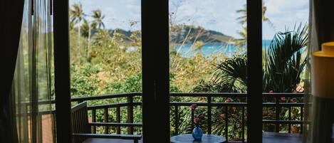 Un balcón con vistas a un paisaje tropical, con palmeras y una montaña.
