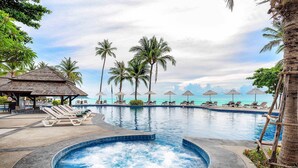 A pool area with lounge chairs, a hot tub, and umbrellas. - Nora Beach Resort and Spa (Koh Samui)