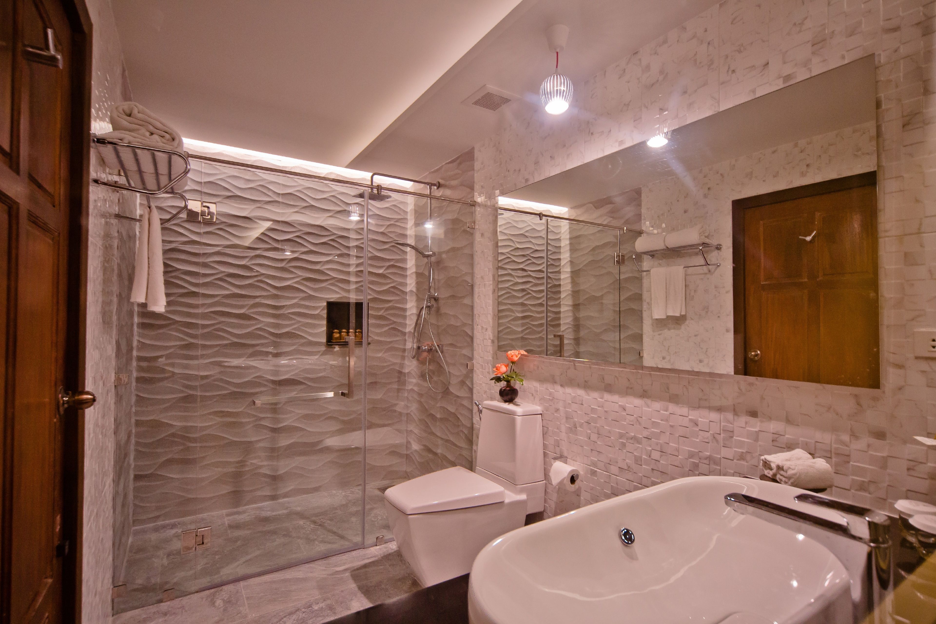 A modern bathroom with a glass-enclosed shower, a white toilet, and a freestanding bathtub.