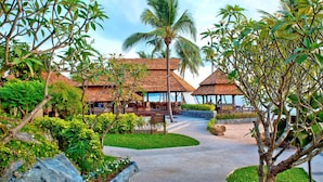 A resort with thatched-roof structures, a paved walkway, and lush greenery. - Nora Beach Resort and Spa (Koh Samui)