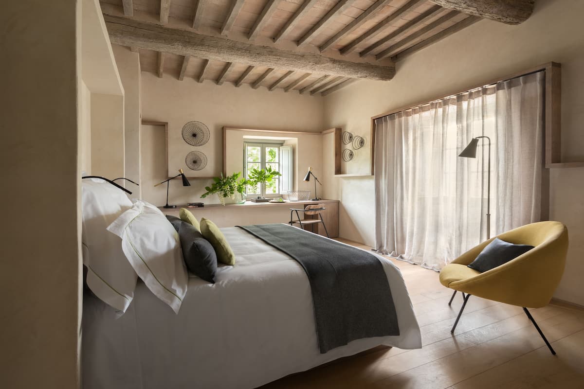Una camera da letto con un letto, una sedia, una scrivania e una finestra con tende.