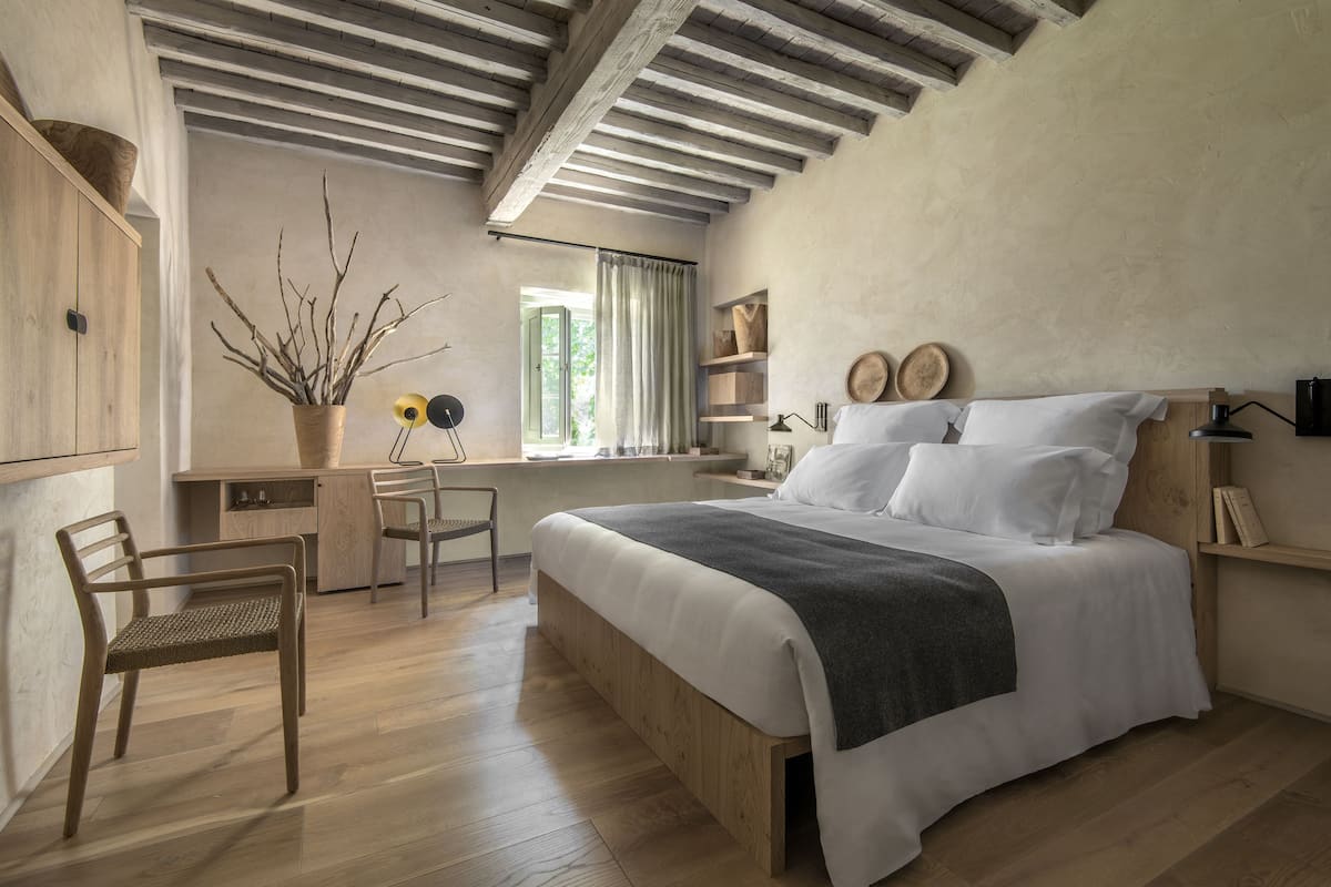 Una camera da letto con un letto di legno, una scrivania, una sedia e una finestra con tende.