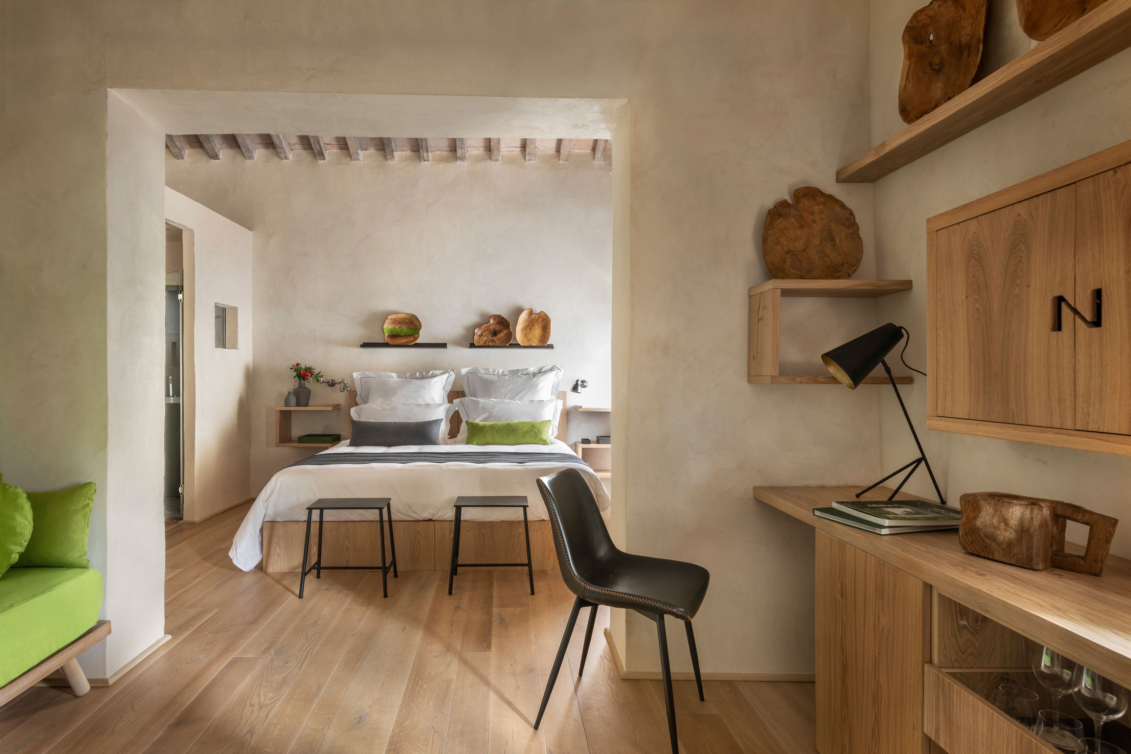 Une chambre moderne avec un lit, un canapé vert, un bureau en bois et une chaise.