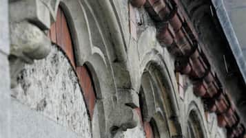 Primer plano de un edificio de piedra con ventanas de arco y tejado de tejas.
