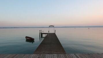 A wooden pier extending into calm water with a boat docked at the end.