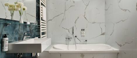 A bathroom with a white sink, a bathtub, and marble-patterned walls.