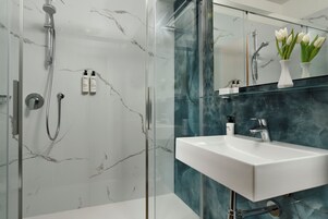 A modern bathroom with a glass-enclosed shower, a white sink, and a marble backsplash.
