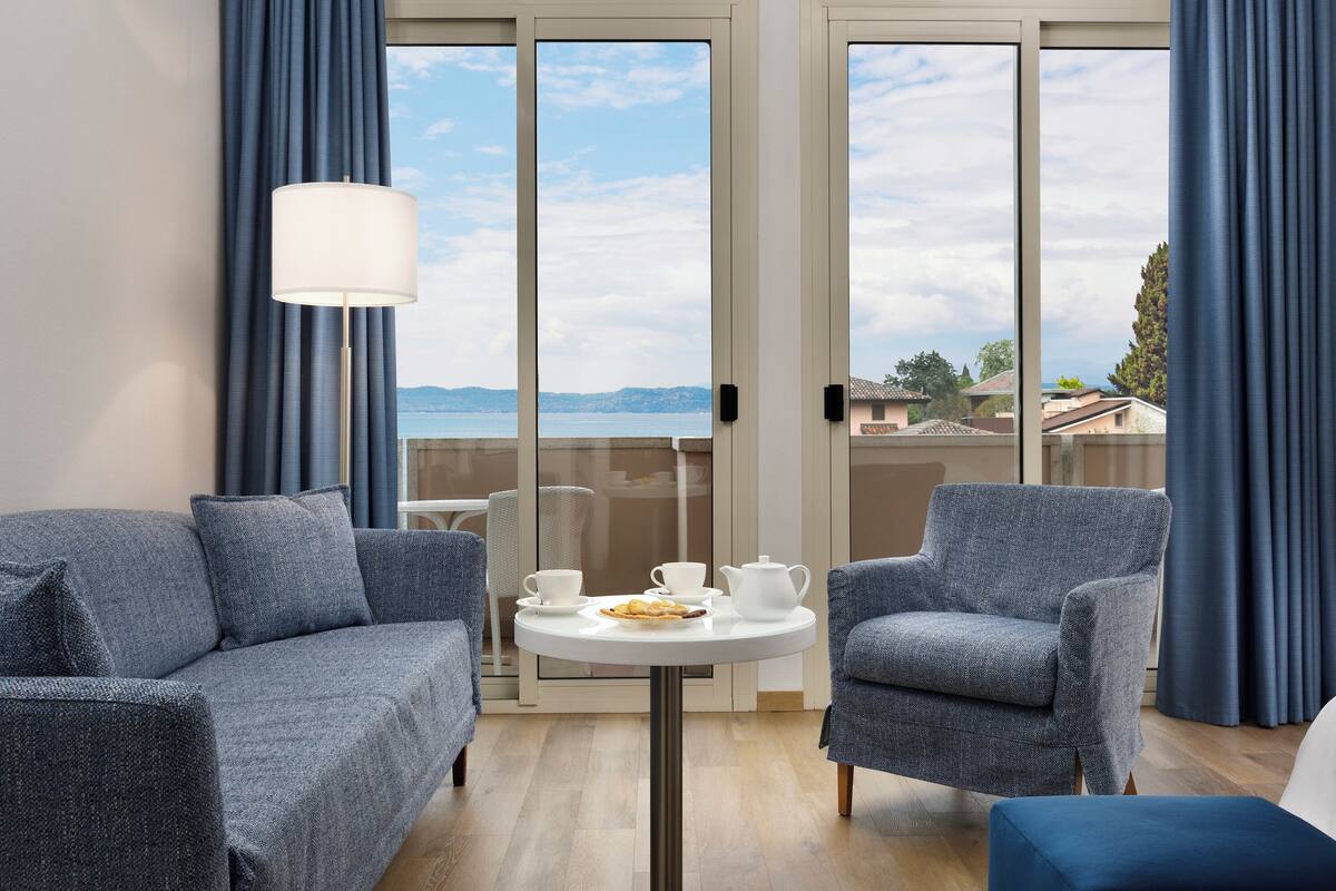 Una habitación con sofá, sillón y una mesita con tetera y tazas.