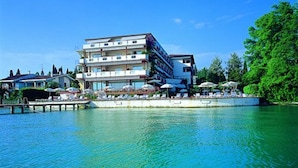 Un hotel de varios pisos con balcones, un muelle y vista al agua.