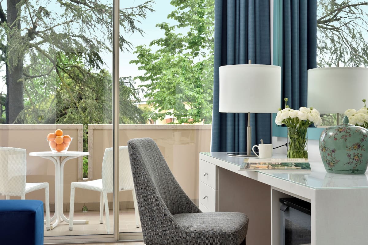 Una habitación moderna con escritorio, sillas, lámpara y un jarrón con flores.