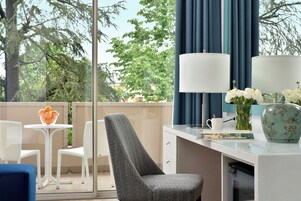 A modern room with a desk, chairs, a lamp, and a vase with flowers.