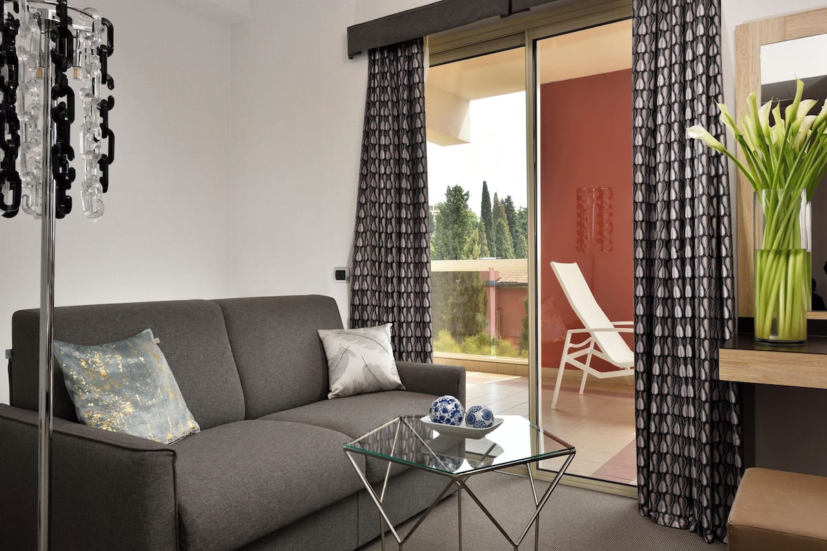 Una sala de estar moderna con un sofá gris, una mesa de centro de vidrio y cortinas estampadas.