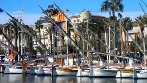 A marina with multiple boats docked, surrounded by palm trees and buildings. - Grand Hôtel Dauphiné Toulon, Boutique Hôtel & Suites (Toulon)