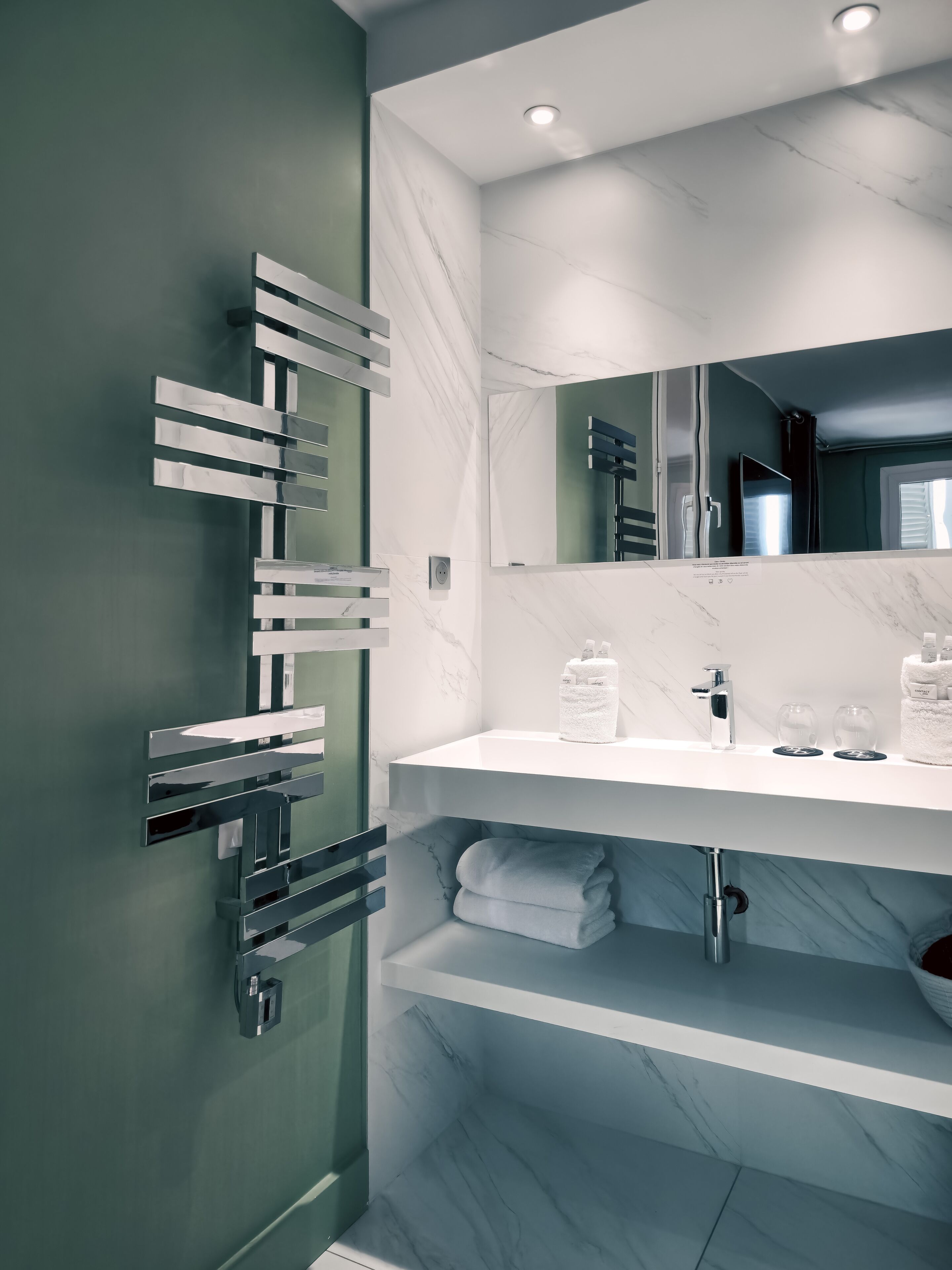 Une salle de bain moderne avec un meuble-lavabo en marbre, un grand miroir et un porte-serviettes.