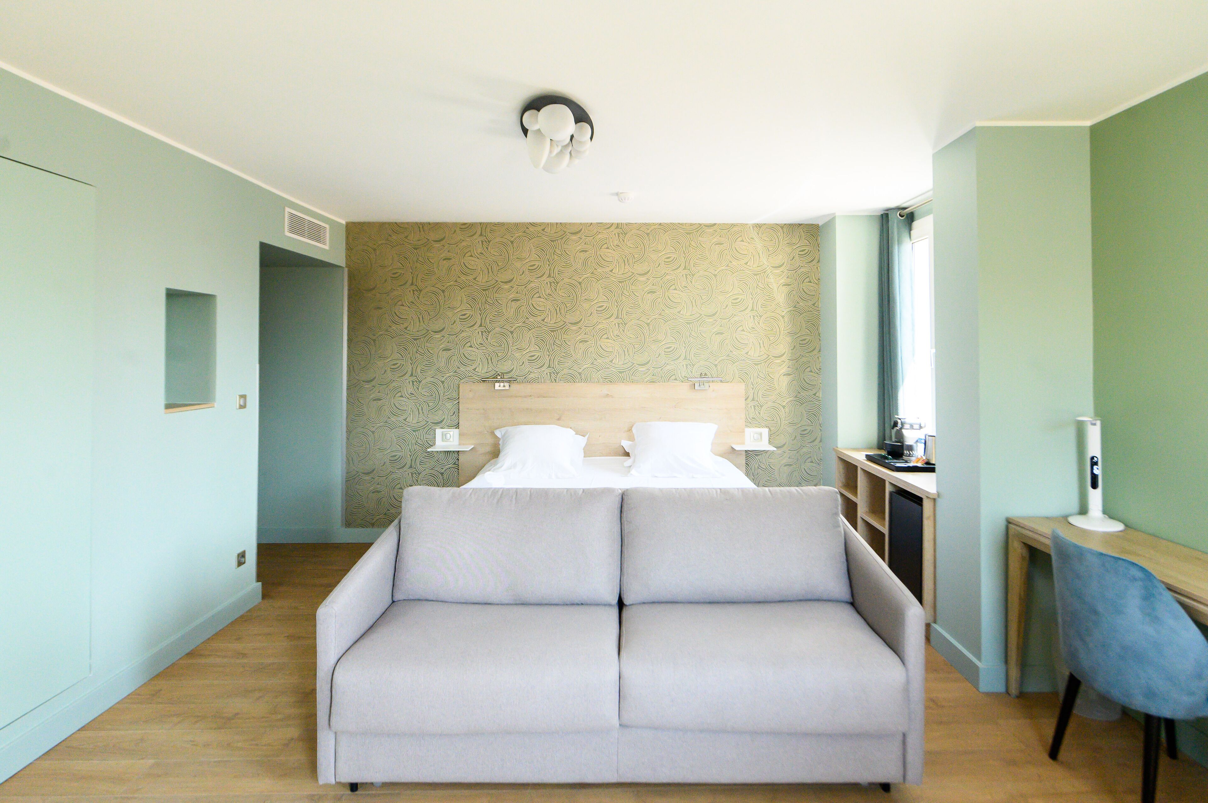 Une chambre d’hôtel moderne équipée d’un lit, d’un canapé, d’un bureau et d’une chaise.