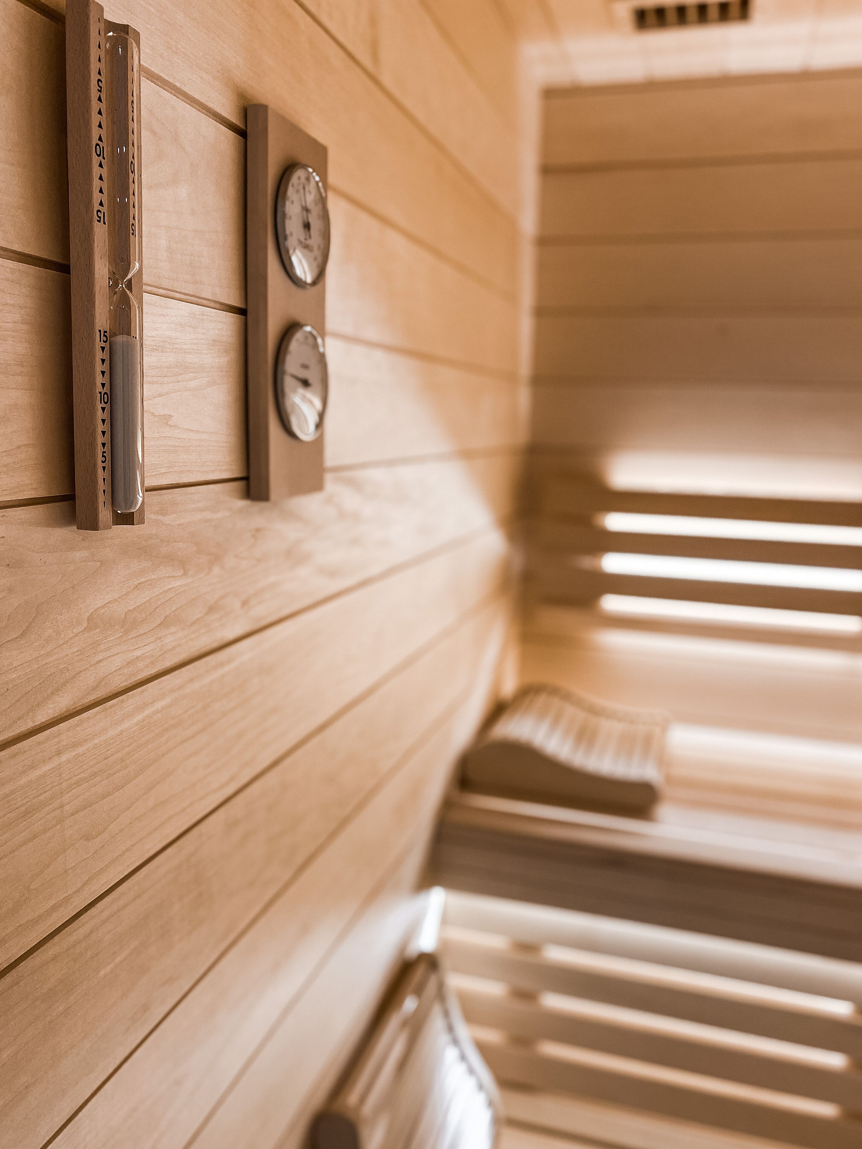 Una sauna con pareti in legno, una panca di legno e due orologi a parete.