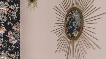 A wall with a floral patterned wallpaper and two wall-mounted decorative items.