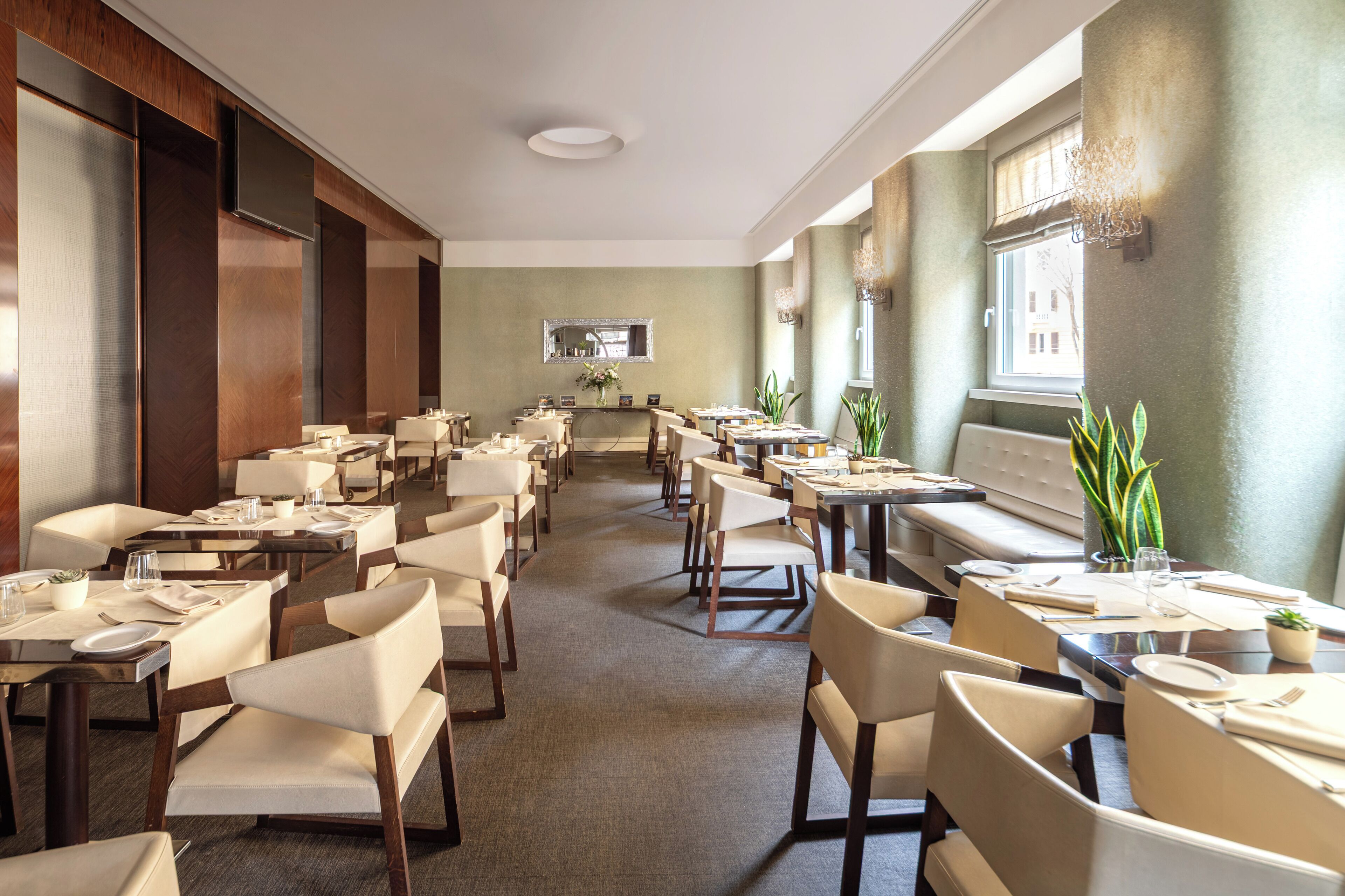 Un restaurant spacieux, doté de nombreuses tables et chaises, d’un grand miroir au mur et d’une fenêtre offrant une belle vue.