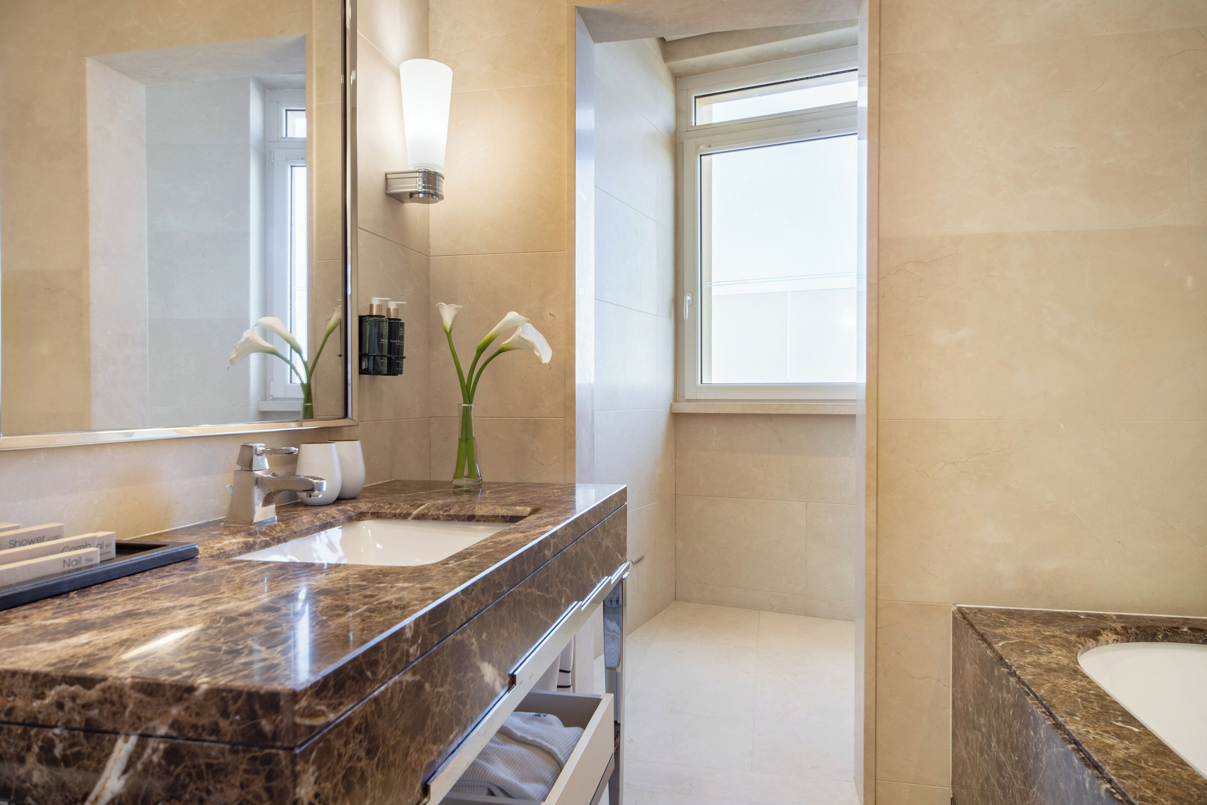 A modern bathroom with two sinks, a large mirror, and a window.