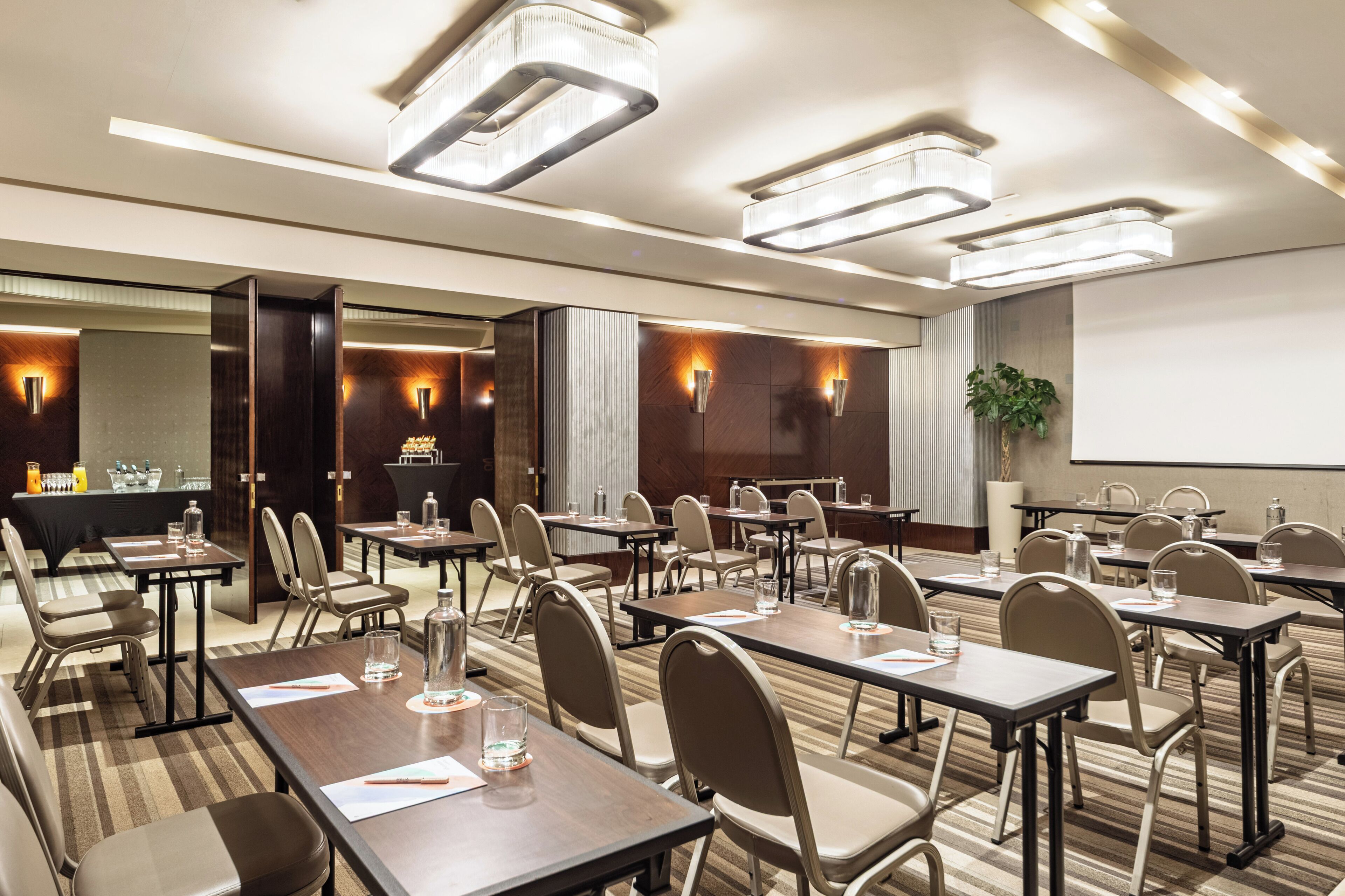 A conference room with tables, chairs, and a projector screen.