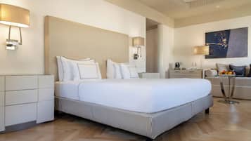 Una habitación de hotel moderna con una cama grande, mesitas de noche, un sofá y un cuadro en la pared.