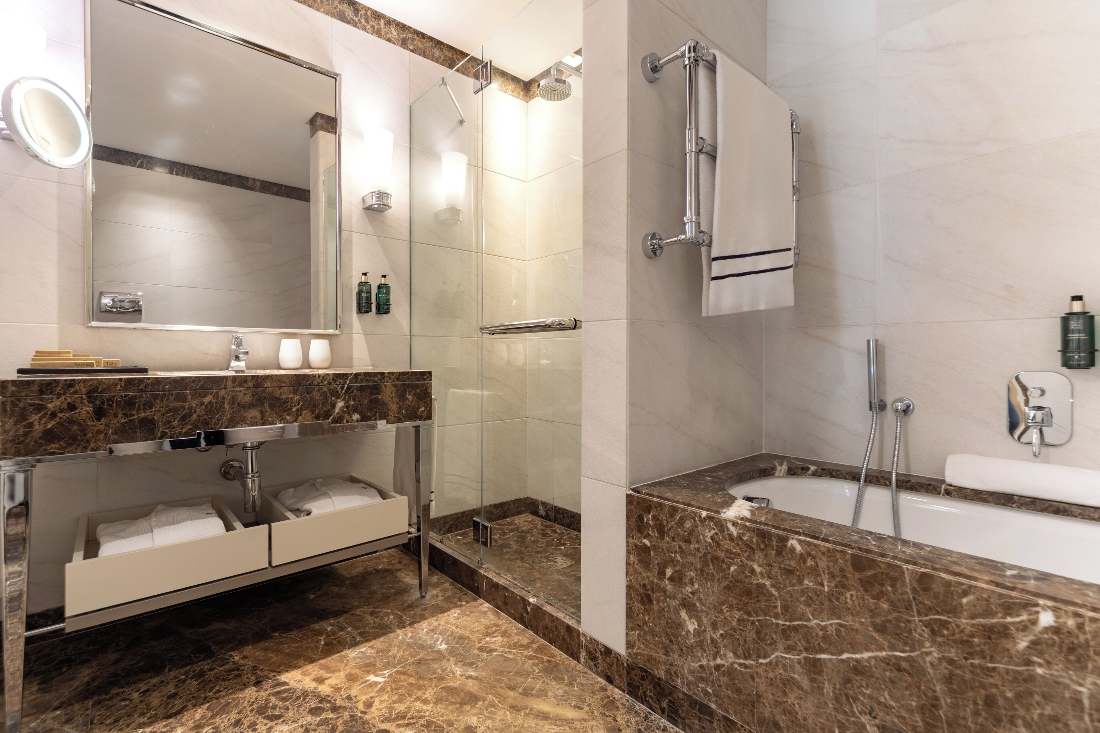 Un baño moderno con tocador de mármol, un espejo grande, ducha con mampara de cristal y bañera independiente.