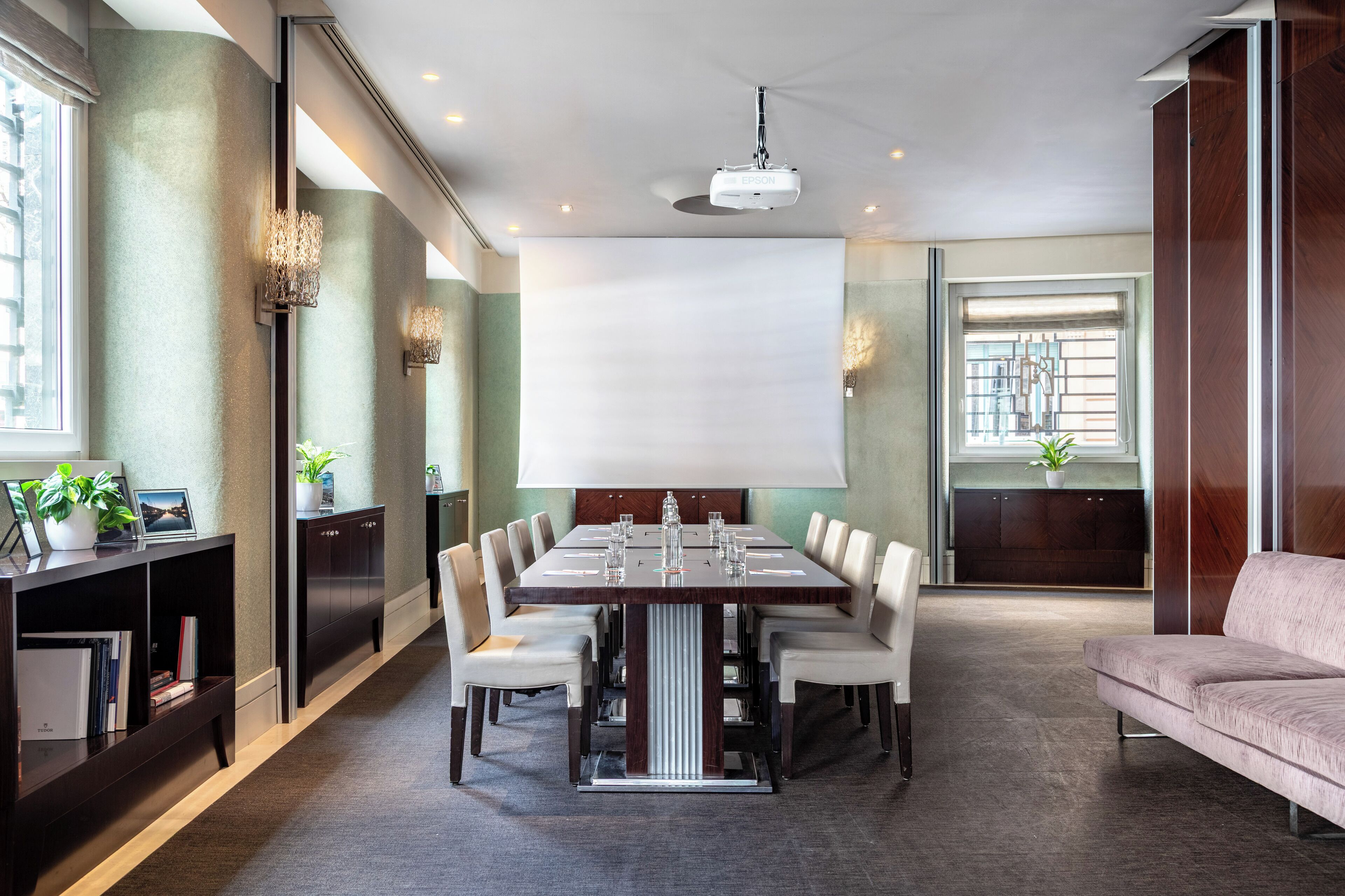 A conference room with a large table, chairs, a projector, and a sofa.