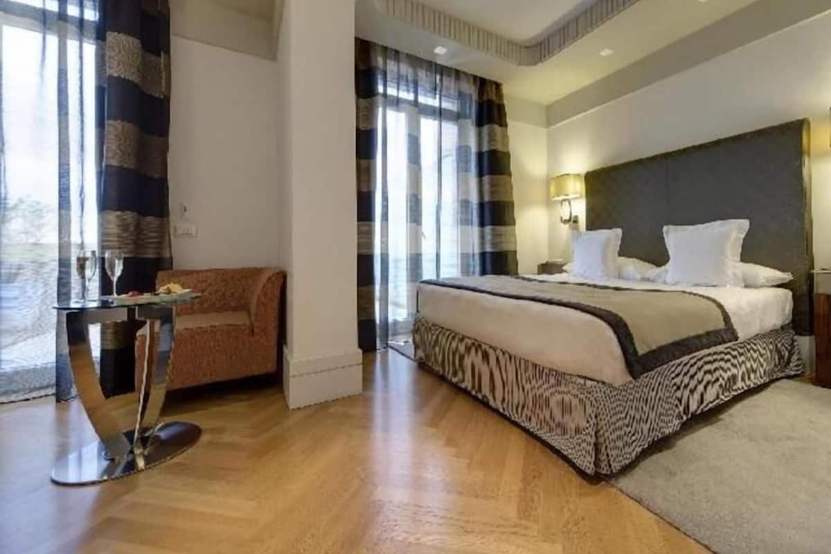 Ett hotellrum med en stor säng, en soffa, ett litet bord och ett fönster med gardiner.