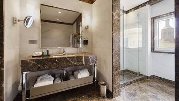 A modern bathroom with a marble vanity, a glass shower enclosure, and a view of the outside.