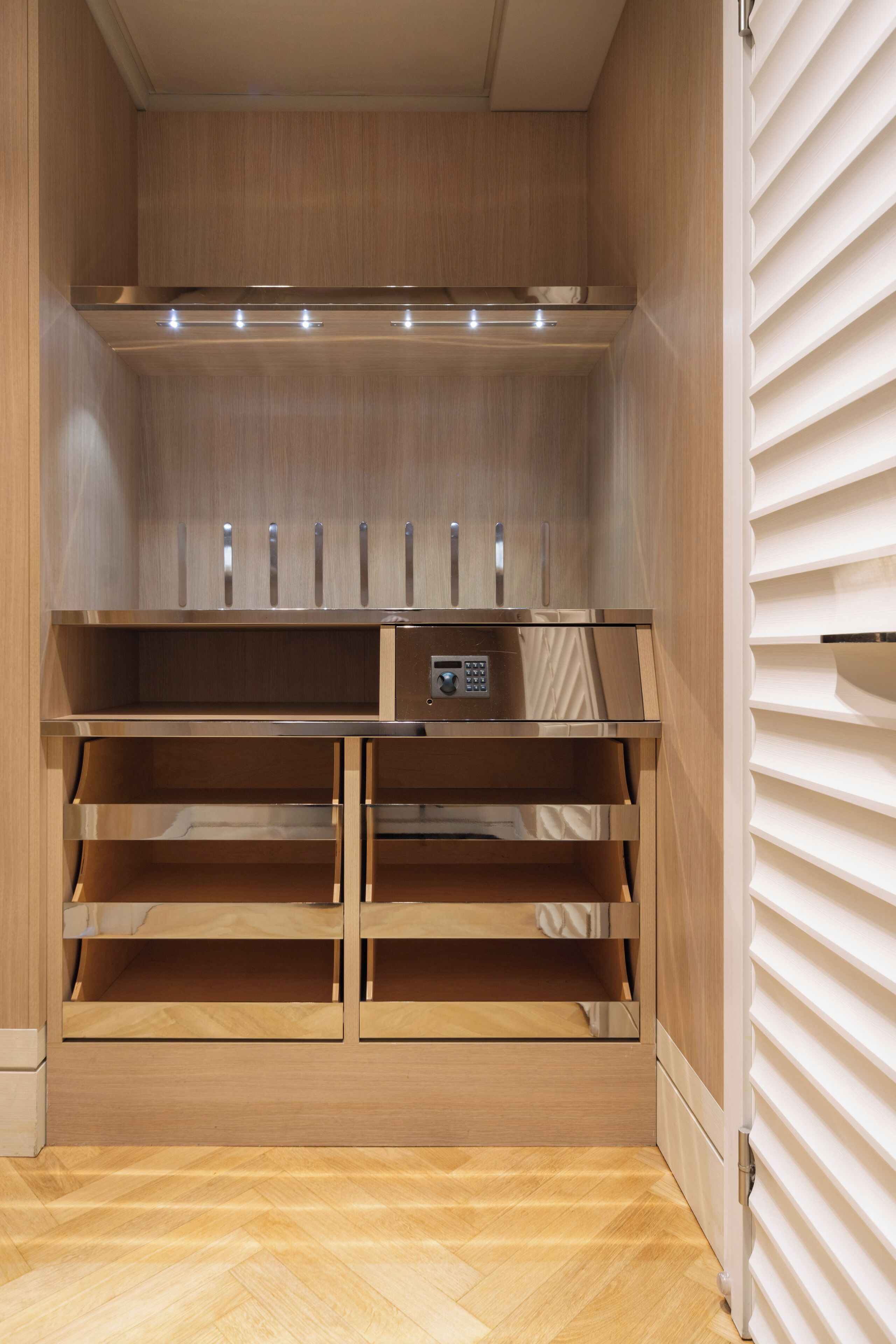 Un dressing moderne et bien éclairé, doté de meubles en bois et d’étagères intégrées.