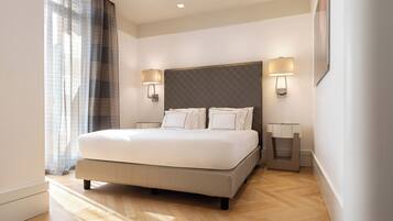 Een moderne hotelkamer met een groot bed, twee nachtkastjes en een hoofdbord met ingebouwde verlichting.